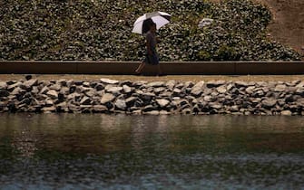 epa10748614 A man uses an umbrella to protect himself from the sun during a heatwave at Echo Park in Los Angeles, California, USA, 15 July 2023. More than a third of Americans are under extreme heat warnings or advisories with records expected to be broken in several cities across the Southern and Western US according to the National Weather Service.  EPA/ETIENNE LAURENT