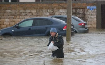 A man walks in a flooded street during an evacuation of residents of the village of Pribrezhnoe in Crimea on November 27, 2023, following a storm. Over 400,000 people in Crimea were left without power on November 27, 2023 after hurricane force winds and heavy rains battered the Russian-annexed peninsula over the weekend. Wind speeds of more than 140 kilometres per hour (about 90 mph) were recorded during the storm, which triggered a state of emergency in some of the peninsula's municipalities. (Photo by STRINGER / AFP) (Photo by STRINGER/AFP via Getty Images)