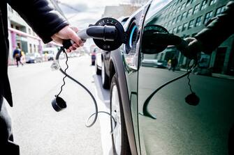 16 April 2021, Berlin: A man removes the plug from a car with plug-in hybrid drive in Berlin-Mitte. The international auto show in China is held alternately in Shanghai and Beijing, this year from April 21 to 28 in Shanghai. Photo: Christoph Soeder/dpa (Photo by Christoph Soeder/picture alliance via Getty Images)