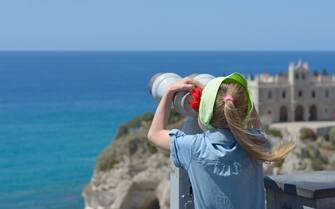 child looking through binoculars at the sea horizon
