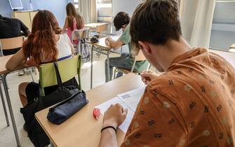 male high school student writing a test in the classroom.