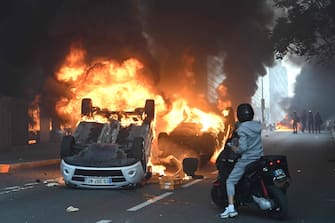 A photo shows cars burning in the street at the end of a commemoration march for a teenage driver shot dead by a policeman, in the Parisian suburb of Nanterre, on June 29, 2023. Violent protests broke out in France in the early hours of June 29, 2023, as anger grows over the police killing of a teenager, with security forces arresting 150 people in the chaos that saw balaclava-clad protesters burning cars and setting off fireworks. Nahel M., 17, was shot in the chest at point-blank range in Nanterre in the morning of June 27, 2023, in an incident that has reignited debate in France about police tactics long criticised by rights groups over the treatment of people in low-income suburbs, particularly ethnic minorities. (Photo by Bertrand GUAY / AFP)