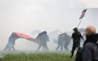 Protesters, surrounded by tear gas, clash with riot mobile gendarmes during a demonstration called by the collective "Bassines non merci", the environmental movement "Les Soulevements de la Terre" and the French trade union 'Confederation paysanne' to protest against the construction of a new water reserve for agricultural irrigation, in Sainte-Soline, central-western France, on March 25, 2023. - More than 3,000 police officers and gendarmes have been mobilised and 1,500 "activists" are expected to take part in the demonstration, around Sainte-Soline. The new protest against the "bassines", a symbol of tensions over access to water, is taking place under thight surveillance on March 25, 2023 in the Deux-Sevres department. (Photo by Thibaud MORITZ / AFP) (Photo by THIBAUD MORITZ/AFP via Getty Images)