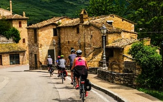 Cyclists peddling through the town of Spello in Umbria Italy