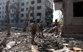 Officers of the special police force "White Angel" Hennadiy Yudin 47(L) and Dmytro Solovyi 23 (R) walk past destroyed buildings and debris during the evacuation of local residents from the village of Ocheretyne not far from Avdiivka town in the Donetsk region, on April 15, 2024, amid the Russian invasion in Ukraine. (Photo by Anatolii STEPANOV / AFP)