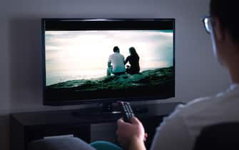 Man watching tv or streaming movie or series with smart tv at home. Film or show on television screen. Person holding the remote control.