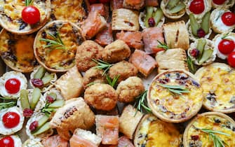 Selection of different flavor canapes on platters and grazing boards. This is the perfect party food with French cheese, ham roll, mini quiches etc
Overhead top view and macro images.