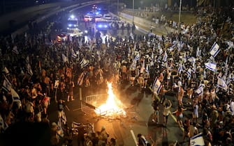 Demonstrators gather around a bonfire as they block a highway during a protest against the Israeli government's judicial reform plan in Tel Aviv on July 24, 2023. Israeli lawmakers on July 24 approved a key clause of a controversial judicial reform plan that aims to curb the powers of the Supreme Court in striking down government decisions. (Photo by JACK GUEZ / AFP) (Photo by JACK GUEZ/AFP via Getty Images)
