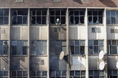 EDITORS NOTE: Graphic content / A firefighter looks out of broken windows at the scene of a fire in a building in Johannesburg on August 31, 2023. At least 20 people have died and more than 40 were injured in a fire that engulfed a five-storey building in central Johannesburg on August 31, 2023, the South African city's emergency services said. (Photo by Michele Spatari / AFP) (Photo by MICHELE SPATARI/AFP via Getty Images)
