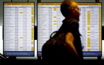 epa10727005 A traveller walks by in front of an information board at Schiphol Airport, The Netherlands, 05 July 2023. Due to bad weather conditions combining strong gusts of wind, rain and poor visibility, the Dutch airline KLM had to cancel a total of 207 flights. The Royal Netherlands Meteorological Institute (Koninklijk Nederlands Meteorologisch Instituut, or KNMI) has issued a code red for parts of the country, warning of 'very heavy wind gusts of 100-120 km / h and even more locally in the provinces of North Holland, Flevoland, Friesland and in the IJsselmeer area.'  EPA/KOEN VAN WEEL