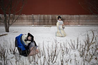 epa11030665 Women in traditional clothes take pictures outside of the Forbidden City in Beijing, China, 14 December 2023. Beijing Meteorological Observatory has issued a Cold Wave alert for 15 and 16 December.  EPA/ANDRES MARTINEZ CASARES
