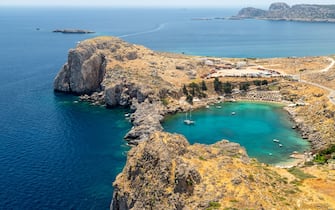 Scenic view from the acropolis of Lindos at the coastline of the mediterranean sea and St. Pauls bay with clear and turquoise water