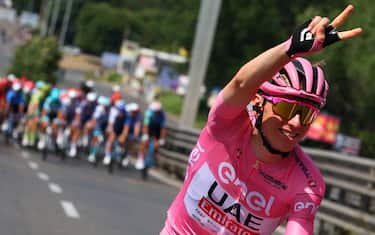 Team UAE's Slovenian rider Tadej Pogacar wearing the overall leader's pink jersey gestures a victory sign as he cycles during the 21st and last stage of the 107th Giro d'Italia cycling race, 125km from Rome to Rome on May 26, 2024. (Photo by Luca Bettini / AFP) (Photo by LUCA BETTINI/AFP via Getty Images)