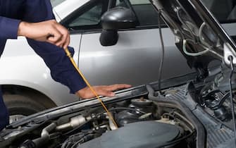 Auto mechanic checking oil level of a car in a garage