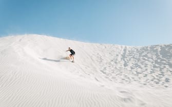 Sand boarding backpackers at the Lancelin sand dunes near Perth, Western Australia