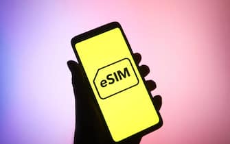 In this photo illustration, eSIM word, name of an embedded integrated programmable SIM card that is embedded directly into a mobile phone, is seen on a smartphone.