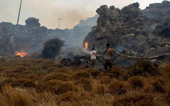 epa10762698 Two men try to put out a wildfire in Kiotari village, on Rhodes island, Greece, 22 July 2023. Although the Fire Department had managed to put out several rekindled blazes on the island over the last few days, the wildfire near the village of Laerma in the island's north keeps expanding and moving eastwards to the Gadoura dam, while residents in the villages of Lardos and Pilonas were told to evacuated their homes on the day, via the emergency number 112. Some 173 firefighters with 35 fire engines and 10 ground teams are battling the blaze, assisted by 3 water bombers and 2 helicopters. Another 31 firefighters with 4 fire engines and 3 ground teams were also expected to arrive from Slovakia. Local authority water tanks are also helping out.  EPA/DAMIANIDIS LEFTERIS