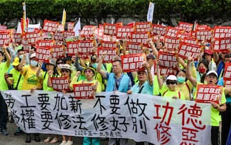 epa11311748 Taiwanese and foreign workers display various placards and chant slogans as they march during the International Labor Day rally in Taipei, Taiwan, 01 May 2024. Thousands of participants from various labor groups demanded the government for better working hours and salary increases.  EPA/RITCHIE B. TONGO
