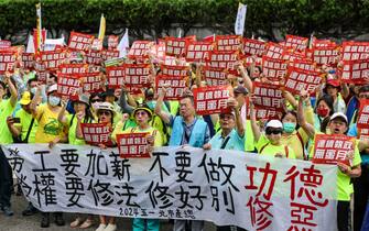 epa11311748 Taiwanese and foreign workers display various placards and chant slogans as they march during the International Labor Day rally in Taipei, Taiwan, 01 May 2024. Thousands of participants from various labor groups demanded the government for better working hours and salary increases.  EPA/RITCHIE B. TONGO