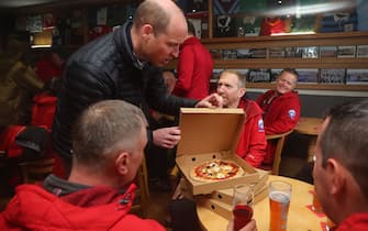 MERTHYR TYDFIL, WALES - APRIL 27: Prince William, Prince of Wales delivers take-away pizzas from a pizza van to members of the Mountain Rescue team, during a visit the Dowlais Rugby Club, in Dowlais, during their 2 day visit to Wales on April 27, 2023 in Merthyr Tydfil, United Kingdom. The Prince and Princes of Wales are visiting the country to celebrate the 60th anniversary of Central Beacons Mountain Rescue and to meet members of local communities. (Photo by Geoff Caddick - WPA Pool/Getty Images)