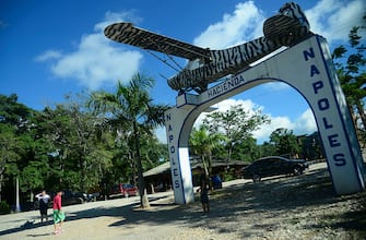 People pose for pictures at the entrance of the Hacienda Napoles theme park, once the private zoo of drug kingpin Pablo Escobar at his Napoles ranch, in Doradal, Antioquia department, Colombia on June 22, 2016.
More than twenty years after drug lord Pablo Escobar died in a gunfight with police, a strange legacy survives him: his pet hippos. Escobar bought four hippos from a zoo in California and flew them to his ranch in the early 1980s. Left to themselves on his Napoles Estate, they bred to become supposedly the biggest wild hippo herd outside Africa -- a local curiosity and a hazard. Estimates put them at about 35 in the area nowadays. / AFP / RAUL ARBOLEDA        (Photo credit should read RAUL ARBOLEDA/AFP via Getty Images)