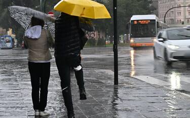 Alcune persone camminano riparandosi dalla pioggia con gli ombrelli a Genova, 8 ottobre 2024. Allagamenti diffusi sul territorio ligure. Scuole chiuse in via precauzionale in molti comuni, allerta arancione nel centro della regione, mentre nel Tigullio e nello spezzino il livello di allerta rossa per i grandi bacini dell'Entella e del Magra.(pioggia,. maltempo, simbolica, pioggia, generica) ANSA/LUCA ZENNARO