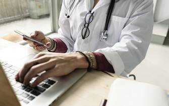 close-up of a female doctor using computer and smartphone