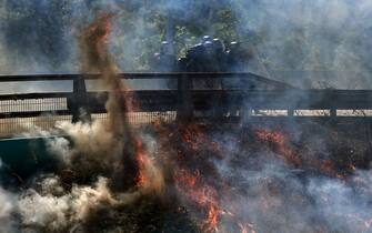 Law enforcement members in riot gear stand in tear gas smoke as they clash with protesters during their march at a demonstration against the construction of a high-speed rail line between Lyon and Torino, in La Chapelle, near Modane, in the French Alps' Maurienne valley, on June 17, 2023. Hundreds of oponents to the Lyon-Torino high-speed rail line demonstrated on June 17 despite a ban on the gathering, of which the details are yet to be determined and despite a heavy police presence in the valley. They set up a makeshift camp on land lent by the municipality of La Chapelle, outside the ban zone announced the day before by the Savoie prefecture. (Photo by OLIVIER CHASSIGNOLE / AFP) (Photo by OLIVIER CHASSIGNOLE/AFP via Getty Images)