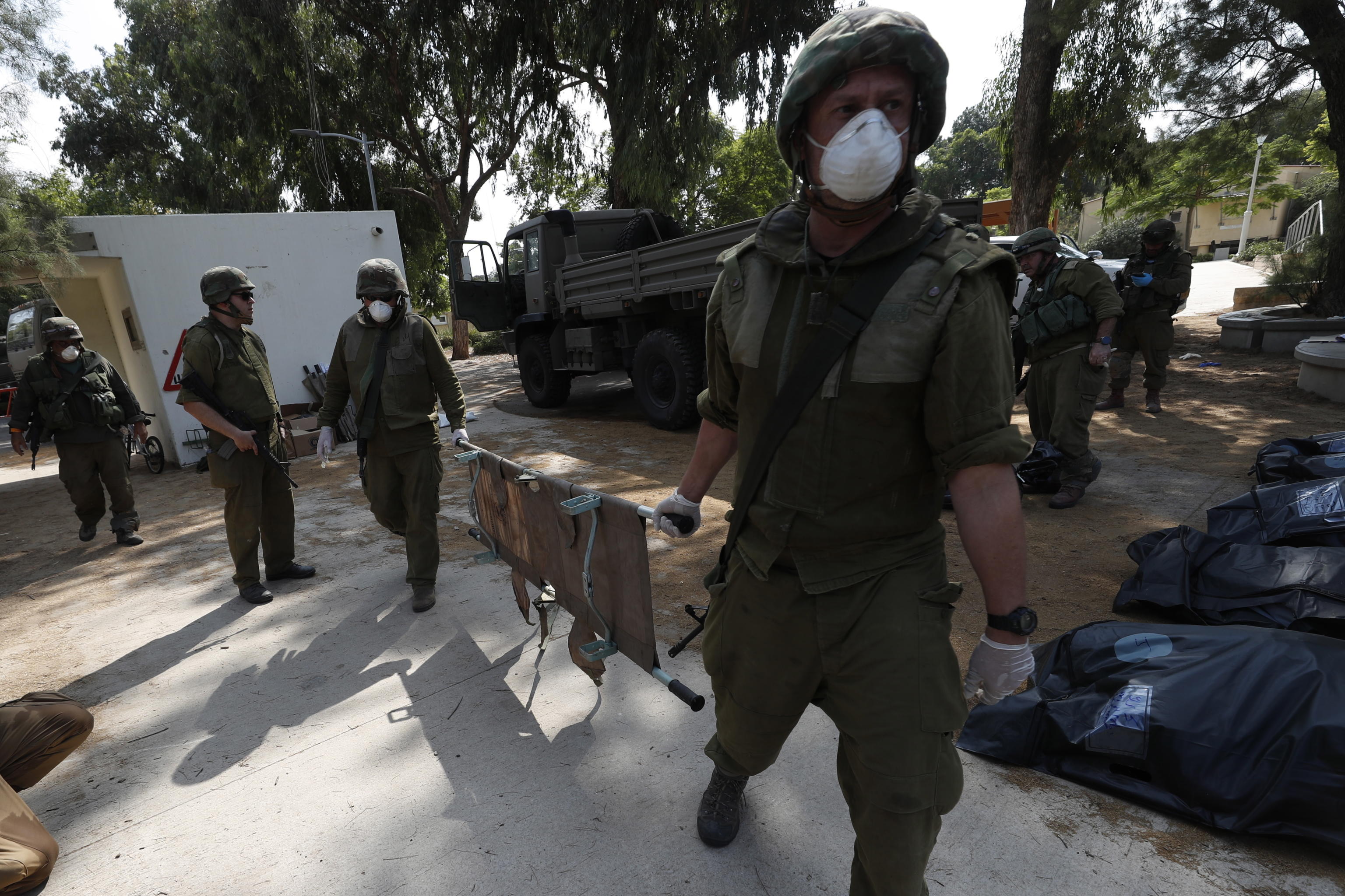 epa10911386 Israeli soldiers take the bodies of Israelis killed in Kfar Aza kibbutz near the border with Gaza, 10 October 2023. More than 900 people have been killed, around 150 were taken as hostages, and 1,500 others injured, according to Israel Defence Forces (IDF), after the Islamist movement Hamas launched an attack against Israel on 07 October. More than 3,000 people, including 1,500 militants from Hamas, have been killed and thousands injured in Gaza and Israel since 07 October, according to Israeli military sources and Palestinian officials.  EPA/ATEF SAFADI