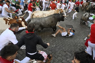 PAMPLONA, SPAIN - JULY 08: People take part in the traditional 'encierro' (bull-run) of the San Fermin Festival in Pamplona, Spain on July 08, 2023. The bull-running fiesta is held annually from 06 to 14 July in commemoration of the city's patron saint. Visitors from all over the world attend the festival. Many of them physically participate in the highlight event - the running of the bulls, or encierro - where they attempt to outrun the animals along a route through the narrow streets of Pamplona's old city. (Photo by Burak Akbulut/Anadolu Agency via Getty Images)