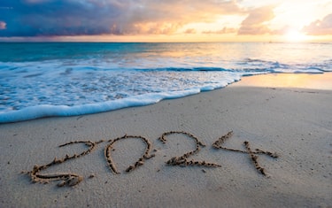 2024 year number handwritten on a sandy beach at sunrise