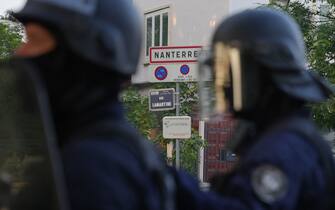 A photo shows a street sign indicating entrance to the city as police in riot gear stand guard  after a demonstration in Nanterre, west of Paris, on June 27, 2023, after French police killed a teenager who refused to stop for a traffic check in the city. The 17-year-old was in the Paris suburb early on June 27 when police shot him dead after he broke road rules and failed to stop, prosecutors said. The event has prompted expressions of shock and questions over the readiness of security forces to pull the trigger. (Photo by Zakaria ABDELKAFI / AFP) (Photo by ZAKARIA ABDELKAFI/AFP via Getty Images)