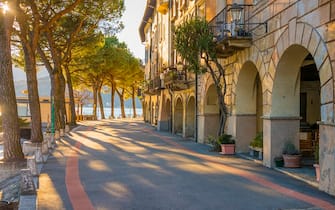 Street with sunlight and old buildings on the waterfront with trees in Morcote, Ticino - Switzerland. (Photo by: Prisma Bildagentur/Universal Images Group via Getty Images)