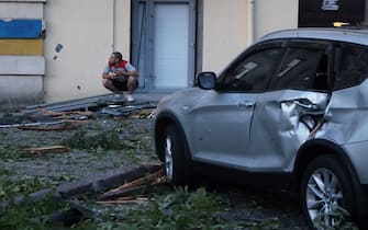 A man sits on his haunches next to a car damaged as a result of a missile strike in Odesa early on July 23, 2023. At least one person was killed and more than 15 wounded in a Russian attack on the southern Ukrainian port city of Odesa, the governor of the region said. (Photo by Oleksandr GIMANOV / AFP) (Photo by OLEKSANDR GIMANOV/AFP via Getty Images)