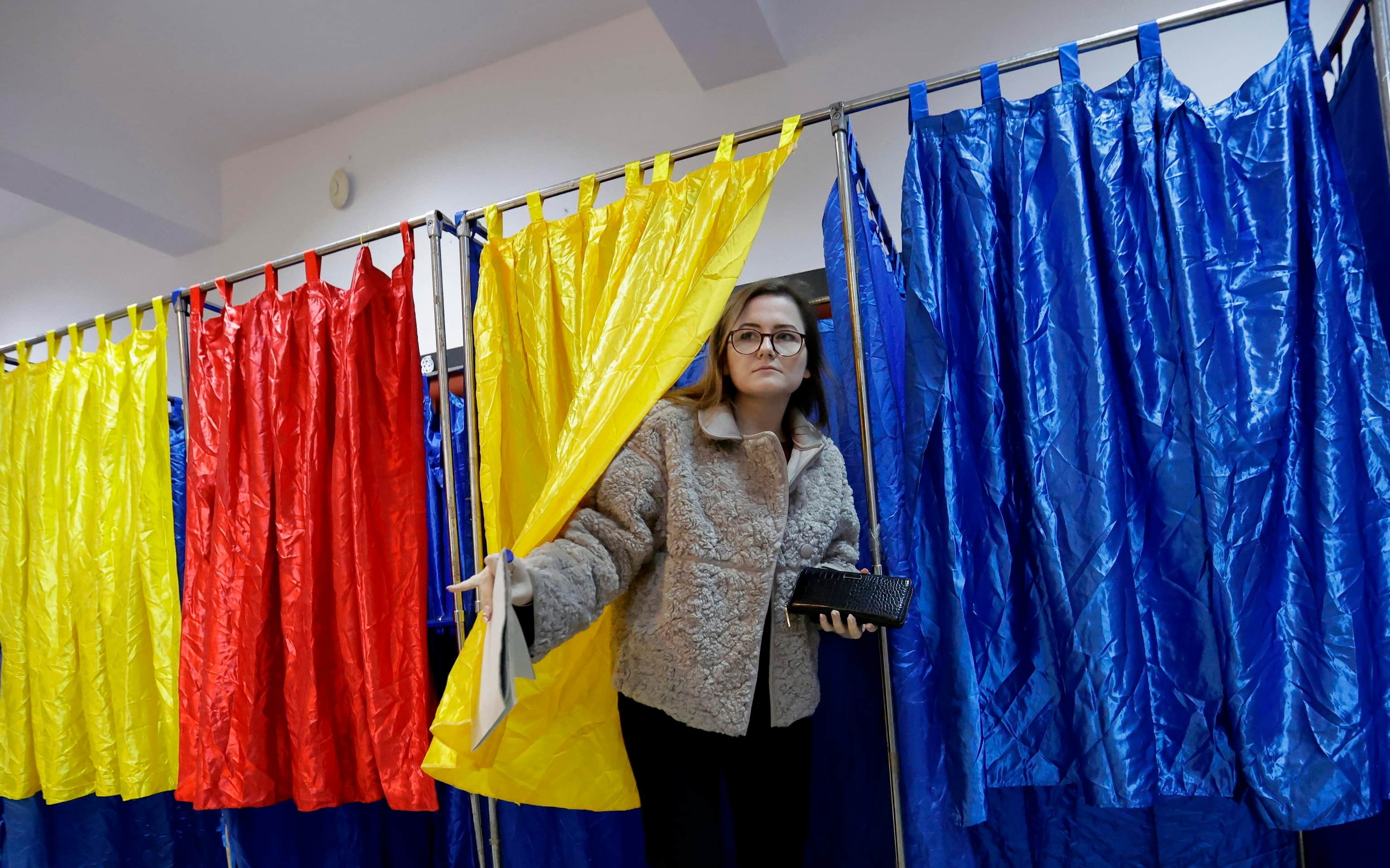 epa11751712 A Romanian woman exits the voting booth after stamping her ballot during the parliamentary elections at Cezar Bolliac Primary School polling station in Bucharest, Romania, 01 December 2024. Approximately 18 million Romanian citizens are expected at the polling stations this weekend for choosing the bicameral parliament members, according to the Permanent Electoral Authority (AEP), of which 989,230 people can express their intention abroad.  EPA/ROBERT GHEMENT