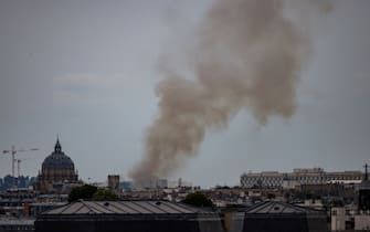 This general view shows smoke rising from a building at Place Alphonse-Laveran near the Dome of the Val de Grace (L) in the 5th arrondissement of Paris, on June 21, 2023. A major fire of unknown origin broke out on June 21, 2023 in a building in central Paris, part of which collapsed, injuring at least one person, according to sources and AFP images. (Photo by Ian LANGSDON / AFP) (Photo by IAN LANGSDON/AFP via Getty Images)