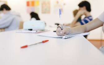 A close up of a high school student writing in her notepad during class.