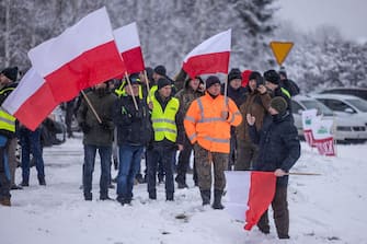 Farmers hold up Polish flags as they block the access to the Polish-Ukrainian border crossing in Dorohusk, eastern Poland on February 9, 2024, during a farmers' protest across the country against EU politics and Ukrainian agricultural products allowed on EU market at low prices. (Photo by Wojtek Radwanski / AFP) (Photo by WOJTEK RADWANSKI/AFP via Getty Images)