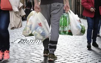 Un uomo con le buste della spesa e una confezione di acqua in bottiglie di plastica dopo l'acquisto in un supermercato di Roma, 1 novembre 2019.
ANSA/LUCIANO DEL CASTILLO
