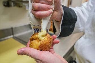 VENICE, ITALY - JANUARY 31: Pastry chef Paul, of "Bonifacio" bakery, fills a "frittella" with cream, "Frittelle" are a typical carnival dessert in Venice on January 31, 2023 in Venice, Italy. The Venice Carnival will begin on February 4 and end on February 21 2023 and will be titled "Take your Time for the Original Signs". (Photo by Stefano Mazzola/Getty Images)