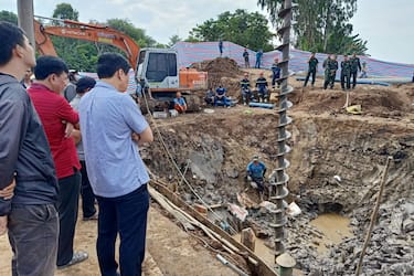 TOPSHOT - Rescuers look down into the site of where a 10-year-old boy is thought to be trapped in a 35-metre deep shaft at a bridge construction area in Vietnam's Dong Thap province on January 2, 2023. - Hundreds of rescuers in Vietnam battled January 2 to free a 10-year-old boy who fell into a 35-metre deep hole on a construction site two days ago. (Photo by AFP) (Photo by STR/AFP via Getty Images)