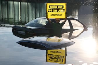 epaselect epa10839232 A Greenpeace protester stands in a lake holding a placard stating 'Auto industry sinks climate protection' in front of the venue of the International Motor Show (IAA) in Munich, Germany, 04 September 2023. The 2023 International Motor Show Germany IAA MOBILITY 2023 takes place in Munich from 05 to 10 September 2023. IAA 2023 will also feature numerous world premieres and has a special focus on electric mobility and digitization.  EPA/ANNA SZILAGYI