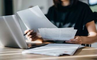 Cropped shot of young Asian woman handling personal banking and finance with laptop at home. Planning budget and calculating expenses. Managing taxes and financial bills. Wealth management. Digital banking habits. Smart banking with technology