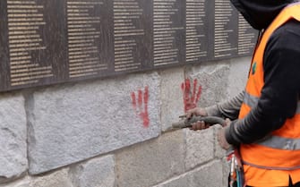 A city employee is at work to clean the "Wall of the Righteous" (Mur des Justes) covered with Red hands graffitis outside the Shoah memorial in Paris, on May 14, 2024, after the monument was vandalized overnight with the president of the Representative Council of French Jewish Institutions (CRIF) denouncing the act as antisemitic. (Photo by Antonin UTZ / AFP) (Photo by ANTONIN UTZ/AFP via Getty Images)