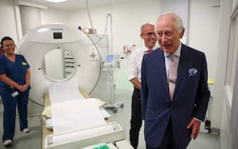Britain's King Charles III (R) shares a laugh with Cancer Research UK's Chief Clinician Charlie Swanton (back R) next to a CT scanner during a visit to the University College Hospital Macmillan Cancer Centre in London on April 30, 2024. Charles is making his first official public appearance since being diagnosed with cancer, after doctors said they were "very encouraged" by the progress of his treatment. (Photo by Suzanne Plunkett / POOL / AFP)