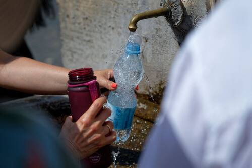 Tourists are filling up water bottles from a public fountain in Saint Peter, Rome, Italy, on July 21, 2024. (Photo by Massimo Valicchia/NurPhoto via Getty Images)