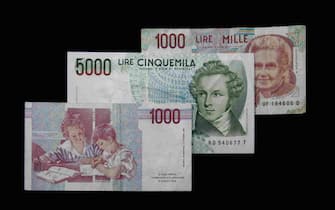View of three Italian Lira banknotes (replaced by the Euro in 2002) on a black background.