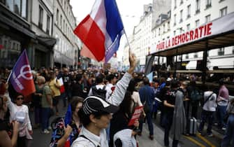 epa11591150 People attend a protest rally in Paris, France, 07 September 2024 as the French left parties called for rallies against President Macron's politics. Protests are taking place across France over the appointment of Michel Barnier as the new French prime minister, after the election that resulted in a National Assembly without a majority and in which the left won the largest number of seats. The slogan (R) reads "For the democracy''.  EPA/YOAN VALAT