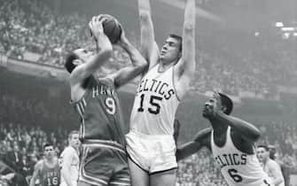 (Original Caption) Leaps to Block. Boston: Tommy Heinsohn (15), of the Boston Celtics, leaps high to block a shot by Bob Petit (9) of the St. Louis Hawks, during their game at the Boston Garden here. Bill Russell (right) of the Celtics, gets ready to leap for the rebound. The Celtics won, 140-122.