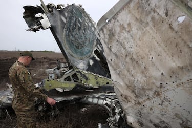 A Ukrainian serviceman examines the remains of a SU-24M aircraft on the outskirts of the town of Izyum, Kharkiv Region, on April 17, 2024, amid the Russian invassion in Ukraine. On March 22, 2022, the crew of the SU-24M bomber, consisting of pilot Oleksiy Kovalenko and navigator Serhiy Verbytsky, bombed a column of Russian heavy equipment, after which their plane was shot down. The pilot Oleksiy Kovalenko died, and the navigator Serhiy Verbytskyi managed to eject and the injured man to get to the Ukrainian positions. Both pilots were awarded the title Hero of Ukraine. (Photo by Anatolii STEPANOV / AFP)